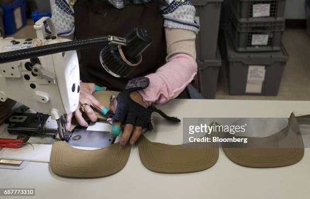 An employee sews rows of supportive stitching on the visors of baseball hats at the Graffiti Caps production facility in Cleveland, Ohio, U.S., on...