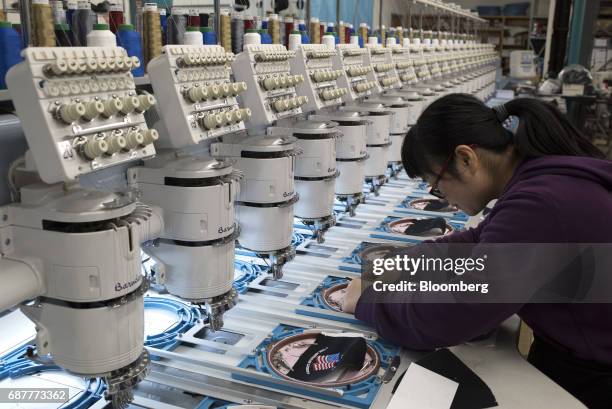 An employee inserts blank fabric panels into embroidery machines to stitch designs at the Graffiti Caps production facility in Cleveland, Ohio, U.S.,...