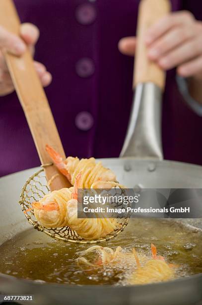 deep-frying noodle-wrapped prawns in wok - schuimspatel stockfoto's en -beelden