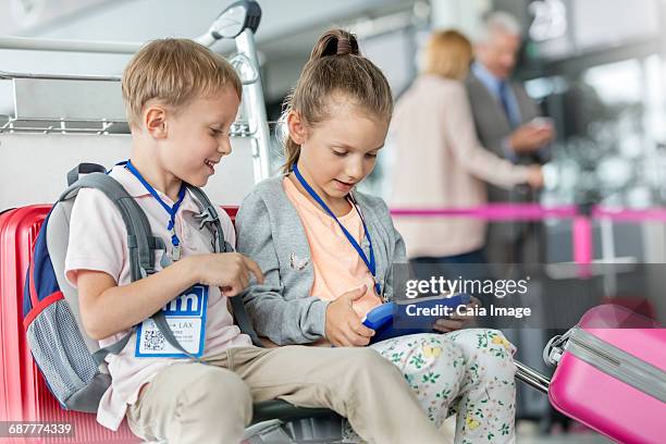 brother and sister using digital tablet in airport departure area - ネックストラップ ストックフォトと画像