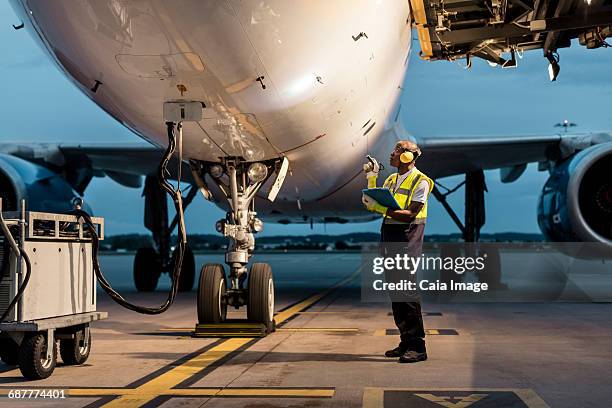 airport ground crew worker checking airplane on tarmac - tanken stock-fotos und bilder