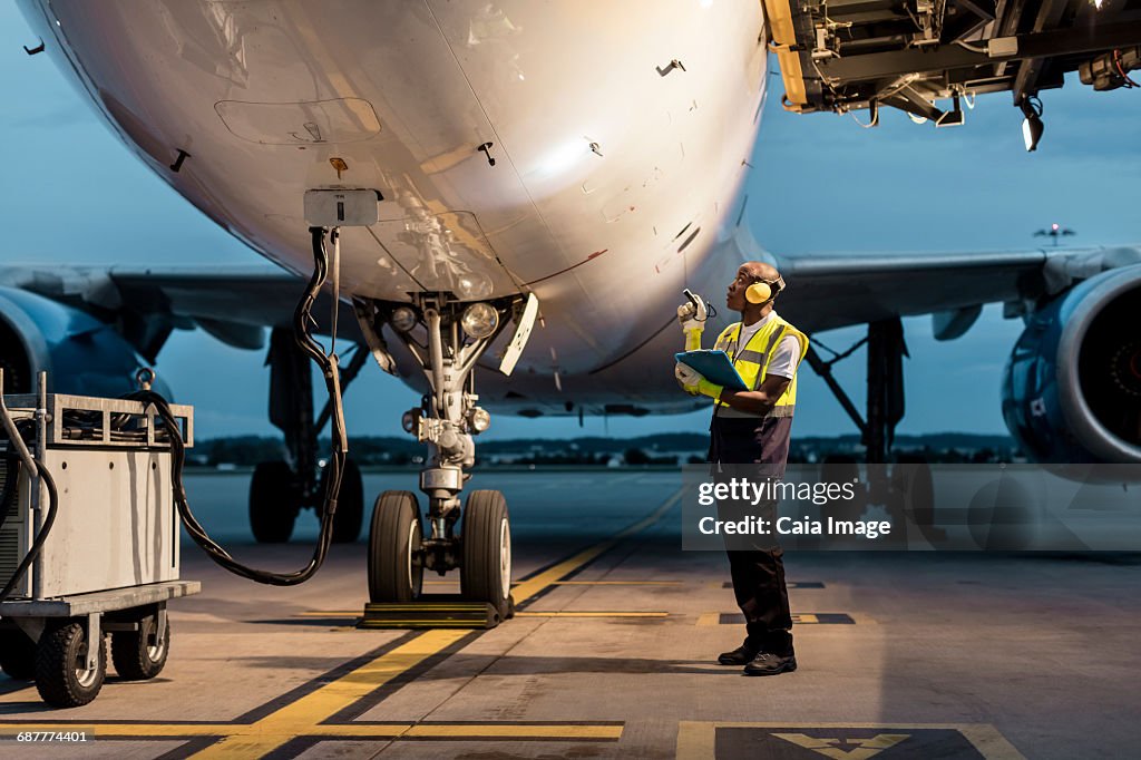 Airport ground crew worker checking airplane on tarmac