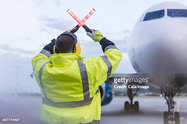 air traffic controller guiding airplane with wand lights on tarmac - air traffic control operator stock pictures, royalty-free photos & images