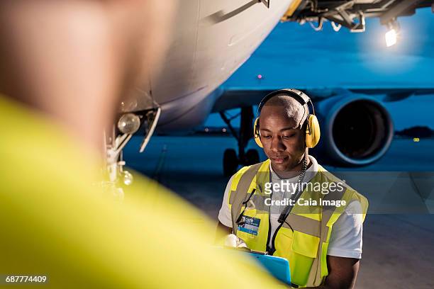 air traffic control ground crew working under airplane on airport tarmac - airport ground crew stock pictures, royalty-free photos & images