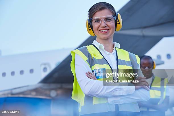 portrait smiling female air traffic controller standing near airplane - air traffic control operator stock pictures, royalty-free photos & images