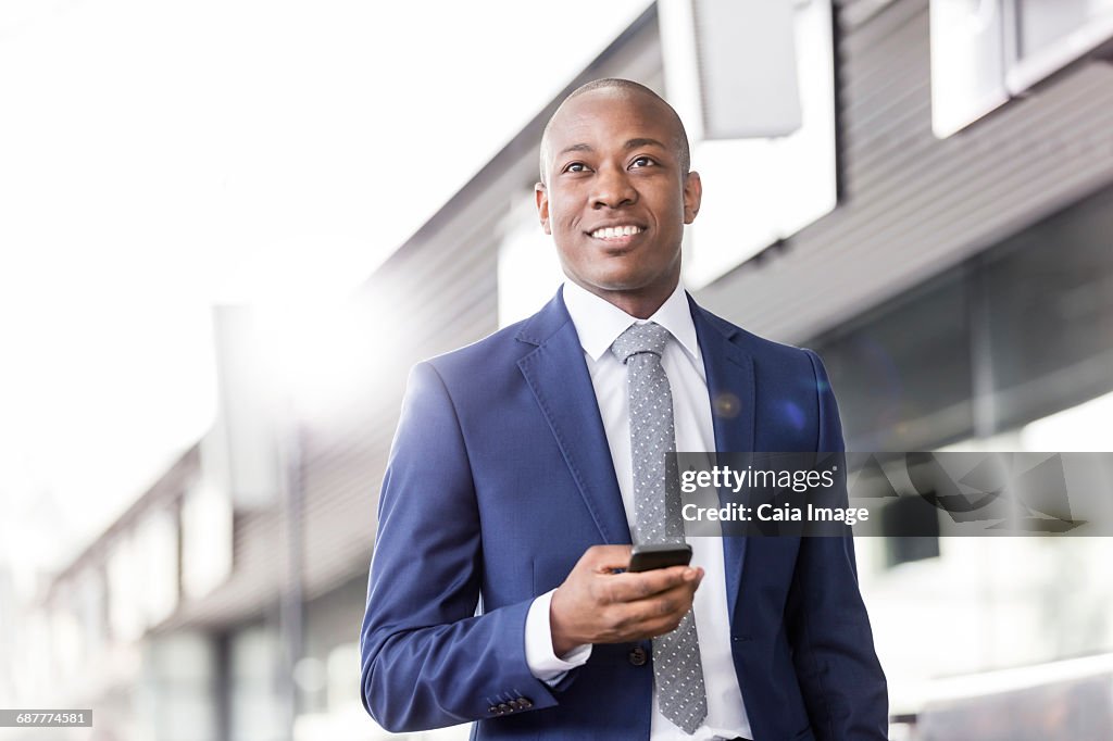 Smiling businessman with cell phone looking away