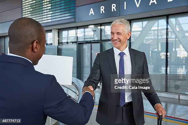 businessmen handshaking in airport concourse - chauffeur stock pictures, royalty-free photos & images