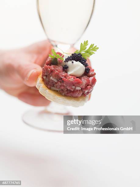 hand holding sparkling wine glass and tuna tartare canap_ - canap�� fotografías e imágenes de stock