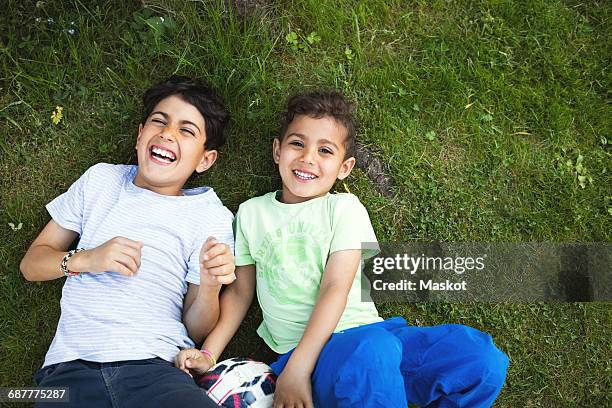 directly above shot of happy boys lying on grassy field - fußball 2 jungs stock-fotos und bilder