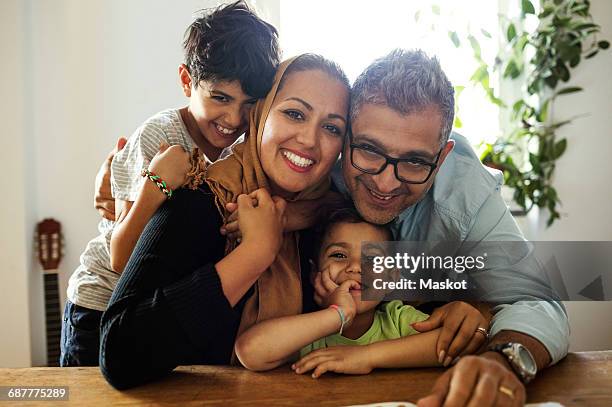portrait of happy family sitting at table - muslim family foto e immagini stock