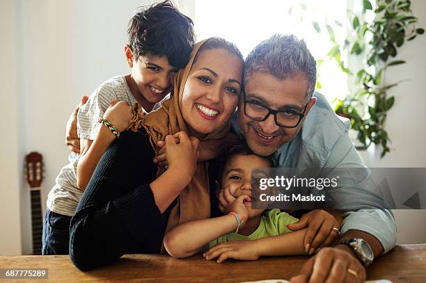 portrait of happy family sitting at table - islam family stock pictures, royalty-free photos & images