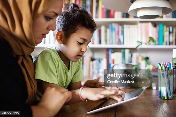 mother and son using digital tablet at table - two young arabic children only indoor portrait stock-fotos und bilder