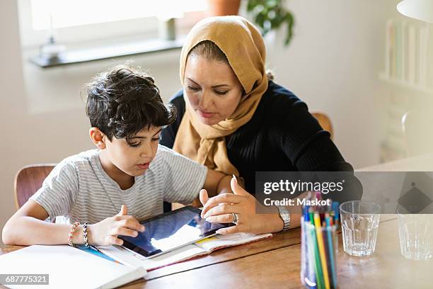 mother and son using digital tablet while studying at home - two young arabic children only indoor portrait stock-fotos und bilder