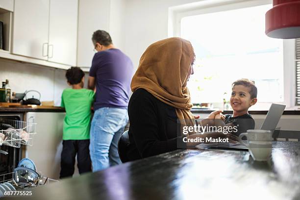 family in brightly lit kitchen - arab mom stock-fotos und bilder