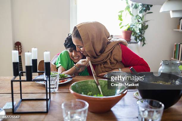 happy mother and son embracing at dining table - arab mom stock-fotos und bilder