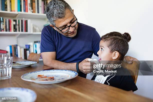 father wiping sons mouth after lunch at dining table - two young arabic children only indoor portrait stock-fotos und bilder