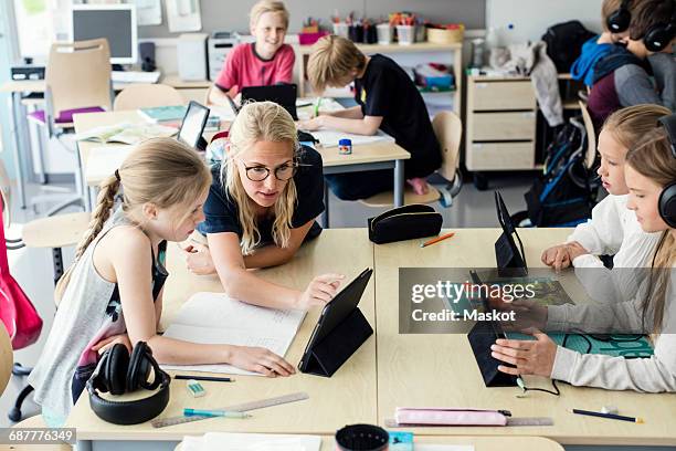 teacher assisting high school girl using digital tablet in classroom - digitalanzeige stock-fotos und bilder