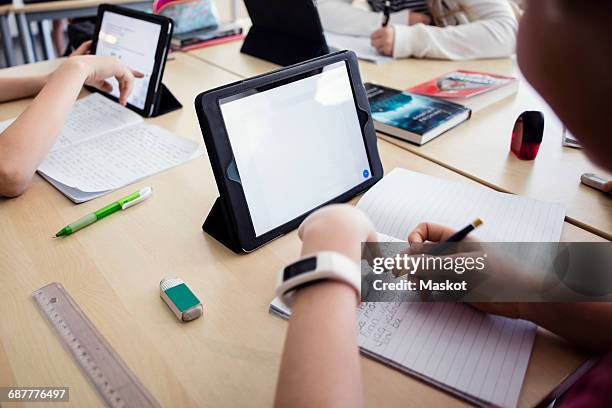 high angle view of students learning through digital tablets in classroom - my tablet tool stock-fotos und bilder