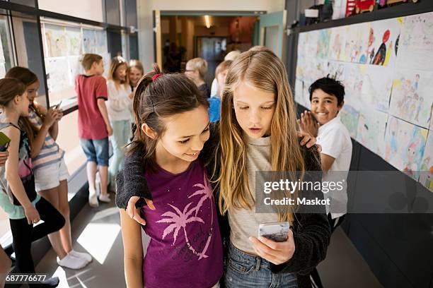 girls using mobile phone with friends in corridor at school - boy pre adolescent phone hand foto e immagini stock