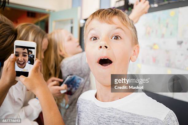 surprised boy standing amidst friends taking selfie in corridor - sayings stockfoto's en -beelden