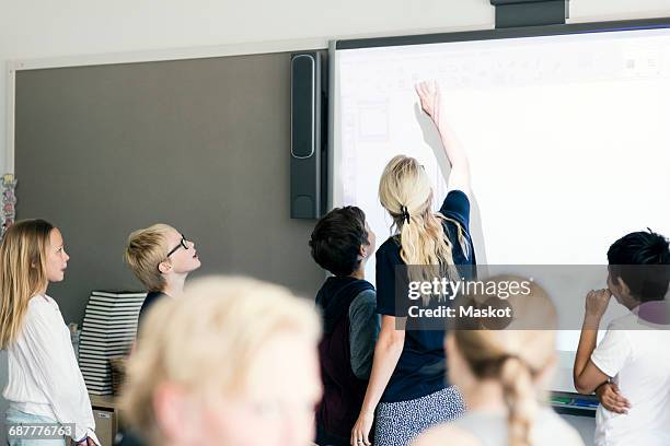 teacher explaining students on whiteboard in classroom - interactive whiteboard foto e immagini stock