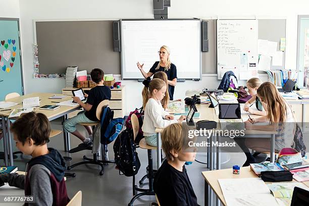 teacher explaining to students in classroom - interactive whiteboard foto e immagini stock