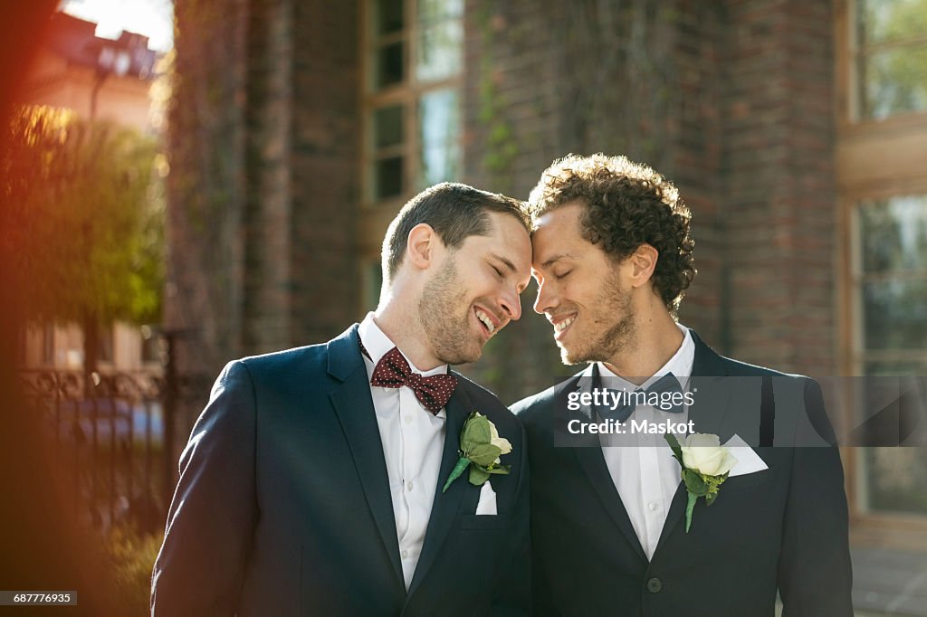 Happy newlywed gay couple standing outdoors