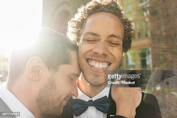 Close-up of gay man embracing cheerful newlywed partner with eyes closed