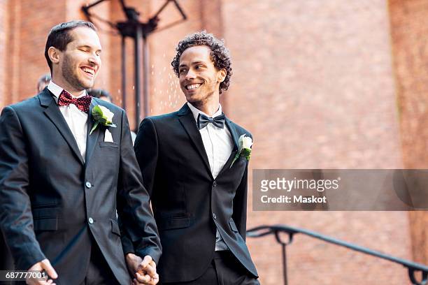 Low angle view of happy gay couple walking while holding hands