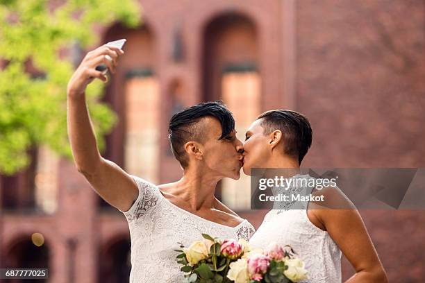 lesbian couple taking selfie from mobile phone while kissing - wedding ceremony kiss stock pictures, royalty-free photos & images