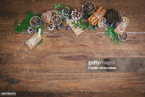 christmas pine cones, pine branches, cinnamon sticks, dried oranges and tags - food wooden table stock-fotos und bilder