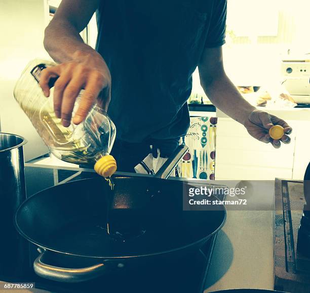 man pouring cooking oil into a wok - electric stove burner ストックフォトと画像