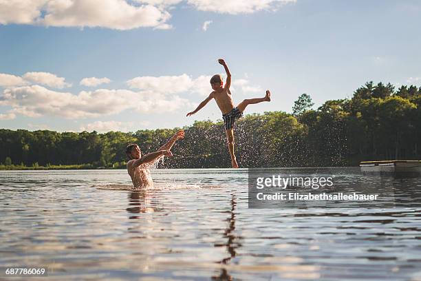 father throwing son in the air in a lake - dad throwing kid in air stockfoto's en -beelden
