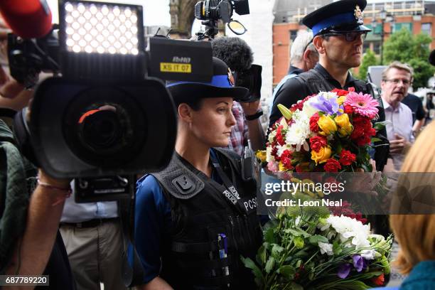 Two Police Community Support Officers are surrounded by members of the media as they wait to lay their flowers with the other floral tributes on May...