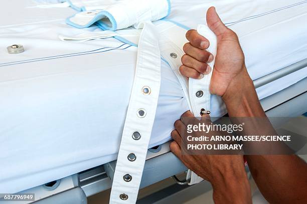 nurse fastening medical restraint to hospital bed - restraining photos et images de collection