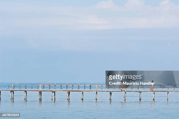 bajau sea gypsy children walk along a pier on mabul island, sabah, malaysia. - bajau stockfoto's en -beelden