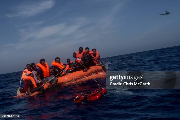 Refugees and migrants are seen waiting in a life raft dropped by a military plane to be rescued by crew members from the c Migrant Offshore Aid...