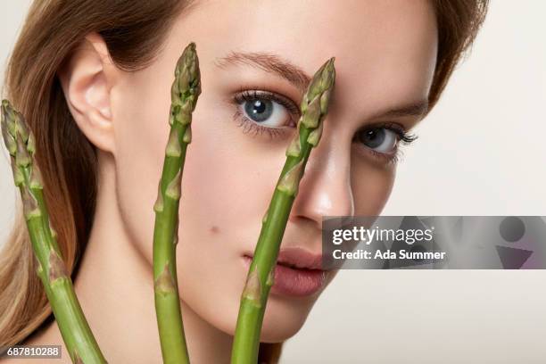 beautiful woman with green asparagus in her hand - antioxidants skin stock pictures, royalty-free photos & images