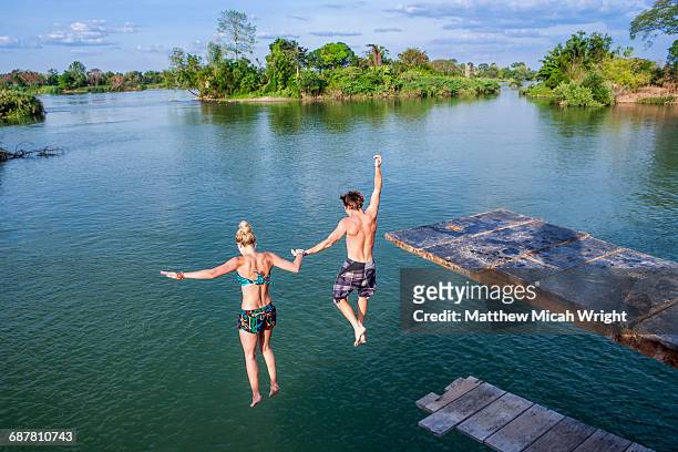a couple jumps into the water, holding hands. - hopptorn bildbanksfoton och bilder