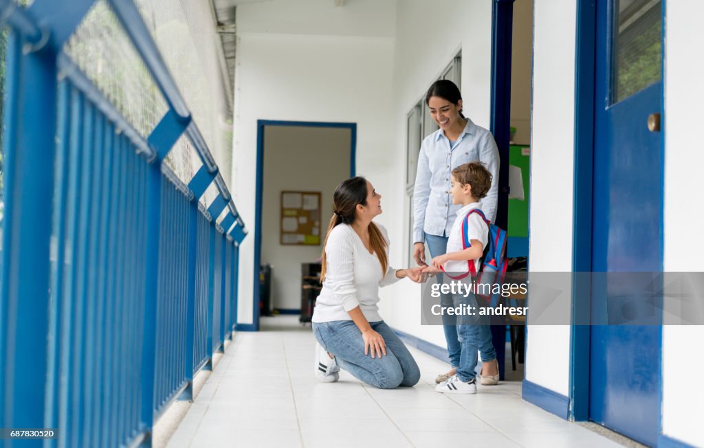 Mutter ihr Kind von der Schule abholen und im Gespräch mit dem Lehrer