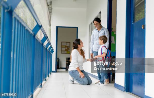 mother picking up her kid from school and talking to the teacher - teachers imagens e fotografias de stock