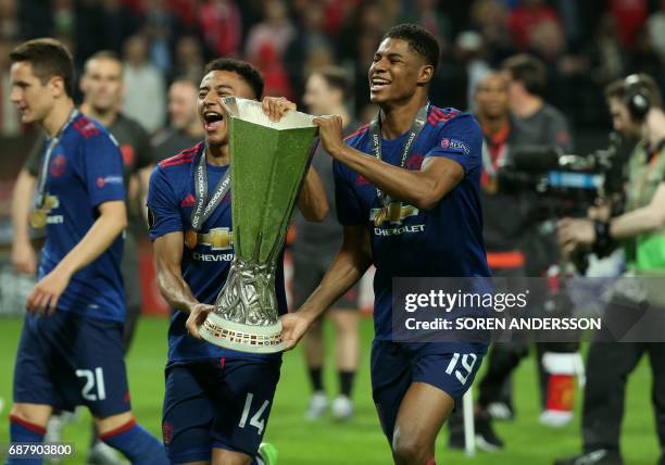 Manchester United's English striker Marcus Rashford and Manchester United's English midfielder Jesse Lingard celebrate with the trophy after their...