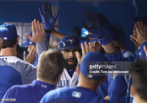 Jose Bautista of the Toronto Blue Jays is congratulated by teammates in the dugout after hitting a three-run home run in the first inning during MLB...