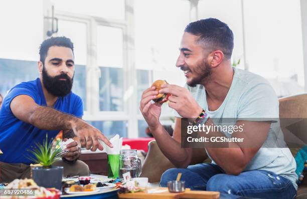 can you pass me the sauce? - male burger eating stock pictures, royalty-free photos & images