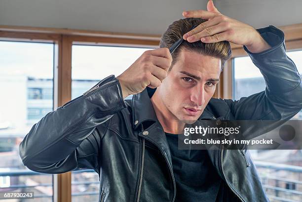 cool dude with a leather jacket combing his hair. - giacca di pelle foto e immagini stock