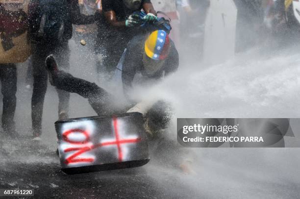 Demonstrator is sprayed by a riot police water cannon during a march against President Nicolas Maduro in Caracas, on May 24, 2017. Venezuela's...