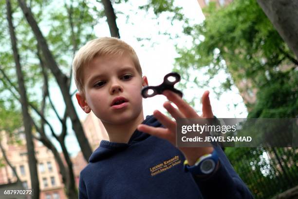 Ten-year-old Louis Wuestenberg plays with a fidget spinner in a park in New York on May 23, 2017. It was supposed to calm nerves, relieve stress and...