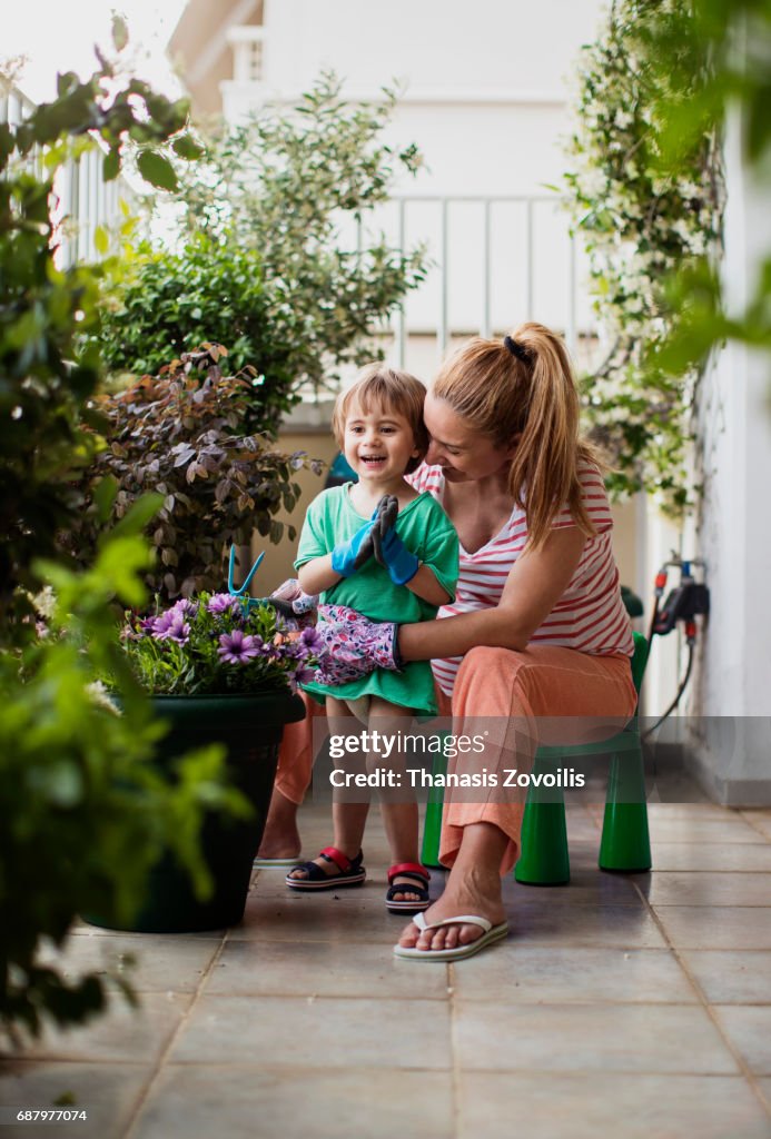 Pregnant mother gardening with her 2 year old boy