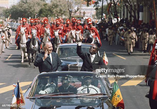 President Georges Pompidou of France pictured with President Leopold Sedar Senghor of Senegal as they wave to spectators and locals from the rear of...
