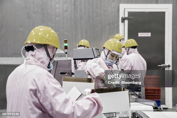 Employees place packages of ham, produced from imported Smithfield Foods Inc. Pork meat, into cardboard boxes at the WH Group Ltd. Facility in...
